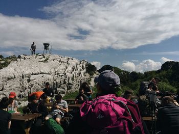 People on landscape against cloudy sky