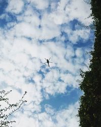 Low angle view of airplane flying against cloudy sky