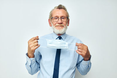 Portrait of senior man holding mask against white background