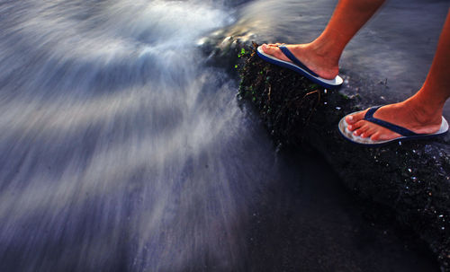 Low section of person standing in water
