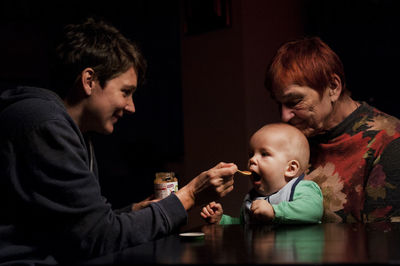 Portrait of mother feeding baby boy on grannys lap