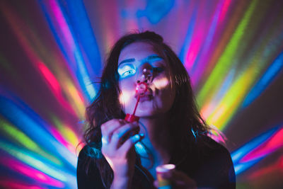 Woman blowing bubbles against illuminated lights