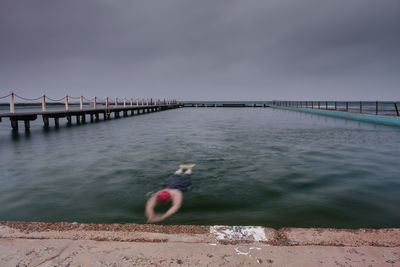 Man in sea against sky