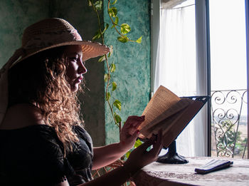 Woman reading book on table at home