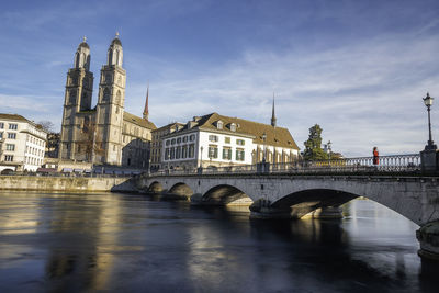 Arch bridge over river against buildings in city