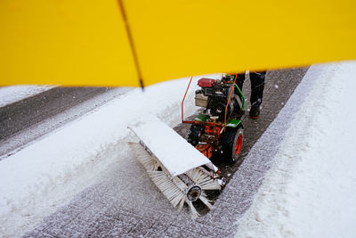 View under umbrella in front machine clearing footpath from snow