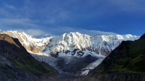 Snowed rocky mountains against blue sky