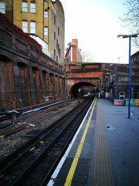 Railroad tracks in city against sky