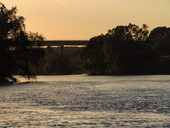 Bridge over river against sky during sunset