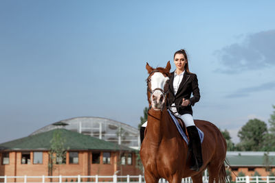 Side view of young woman with horse on field against sky