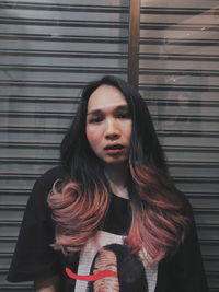 Portrait of young woman standing against wall