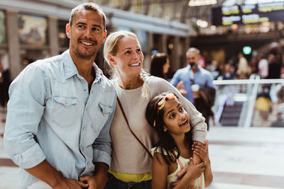 Smiling parents with daughter waiting at railroad station