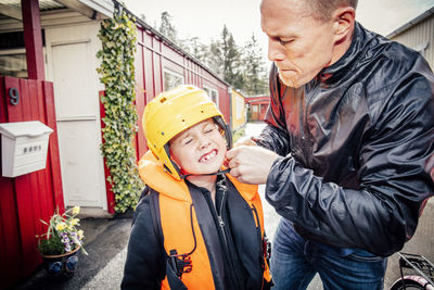 Father helping son with helmet outdoors