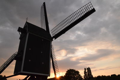 Low angle view of traditional windmill against sky during sunset