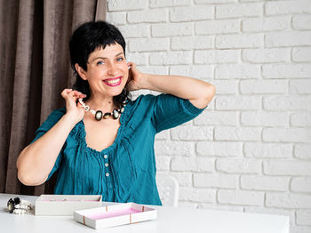 Portrait of a smiling young woman against wall