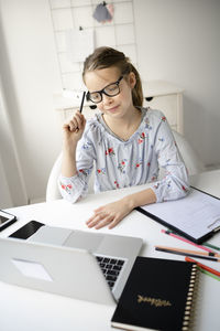 Young woman using mobile phone while sitting on table