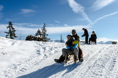 People with dog on snowcapped mountain against sky