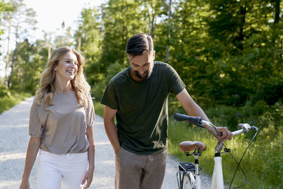 Side view of smiling friends riding bicycles in park