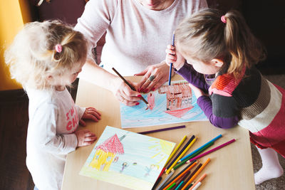 High angle view of mother drawing with daughters at table