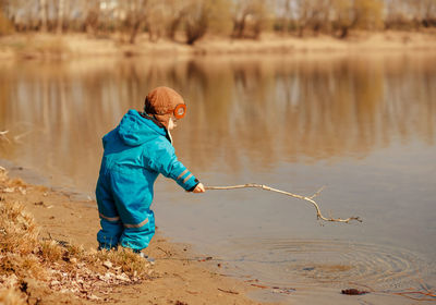 Side view of boy holding stick in water