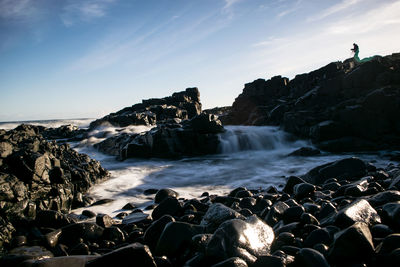 Rocks at sea shore against sky