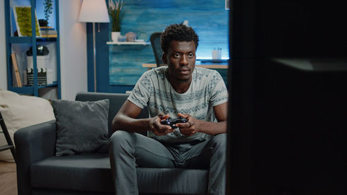 Young man using mobile phone while sitting on sofa at home