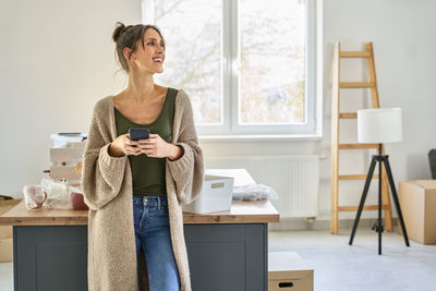 Portrait of young woman standing by window