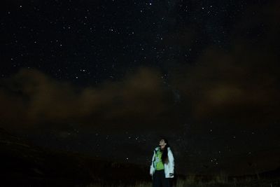 Woman standing against sky at night