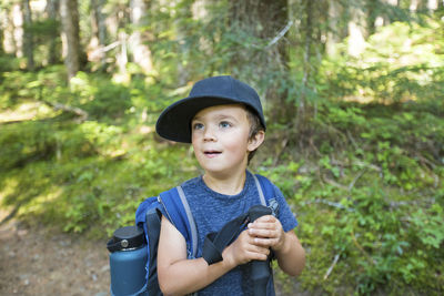 Portrait of young male hiker wearing backpack in forest.