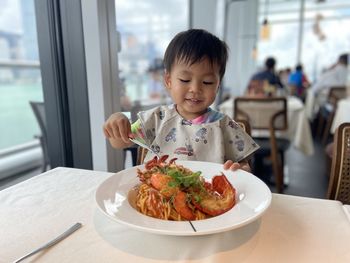 Portrait of asian boy eating food in restaurant