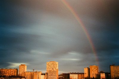 Rainbow over buildings in city against sky