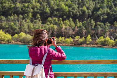 Rear view of woman photographing against sky