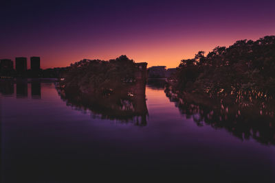 Reflection of silhouette trees in lake against sky during sunset