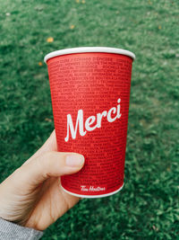 Close-up of hand holding red text on grass