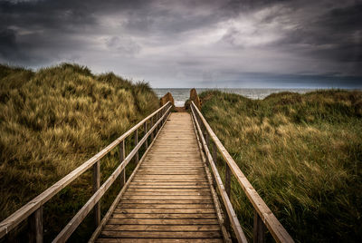 Footbridge over sea against sky