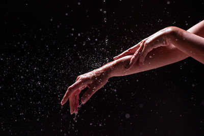 Close-up of hand splashing water against black background