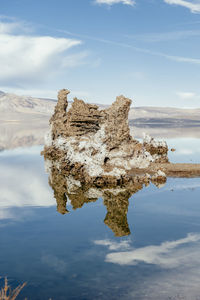 Rock formation in lake against sky