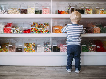 Rear view of boy standing against shelves in store