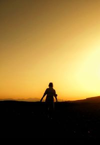 Silhouette of woman on landscape at sunset