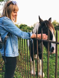 Side view of woman touching horse at ranch