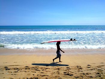 Boy on beach against clear sky