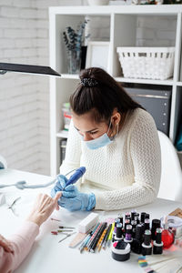 Young woman wearing glove and mask working at salon
