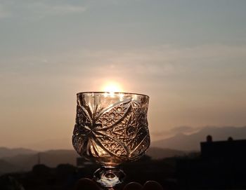 Close-up of wine glass against sunset sky