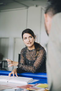 Confident businesswoman explaining male colleague during meeting in creative office