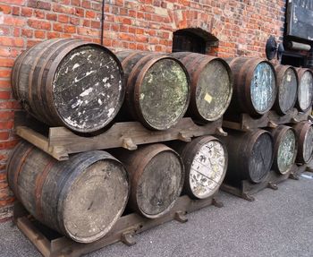 Stack of barrels by brick wall