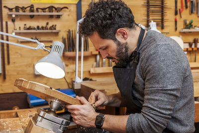 Side view of carpenter working in factory