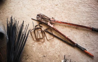 Directly above shot of metal rods and work tool on concrete