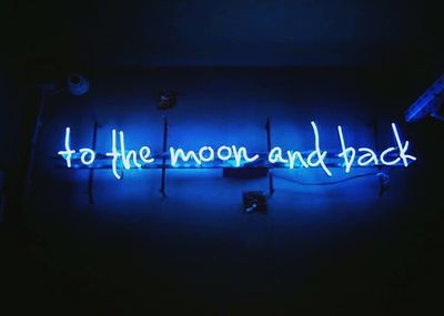 Illuminated text on blue wall at night