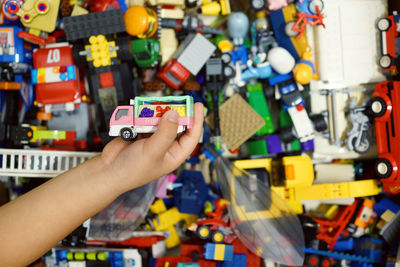 Cropped hand of boy holding toys at home