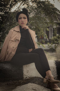 Portrait of young woman looking away while sitting outdoors